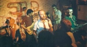 Redonditos de Ricota no El Cemento (na frente Carlos El Indio Solari de gravata torta, o resto da banda no palco improvisado e com uma parede de tijolo à vista atrás)